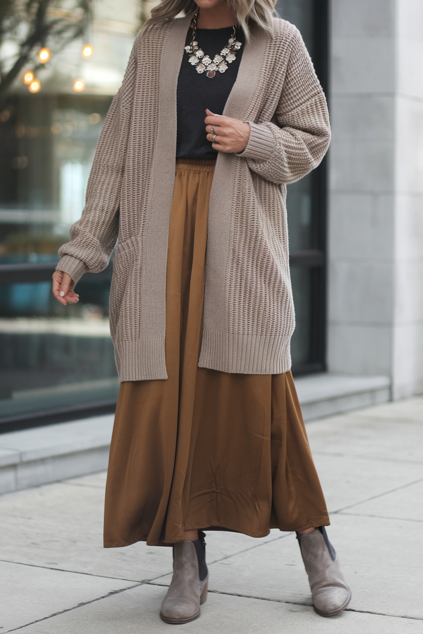 Fashionable individual in a flowy brown skirt and oversized cardigan against an urban backdrop.