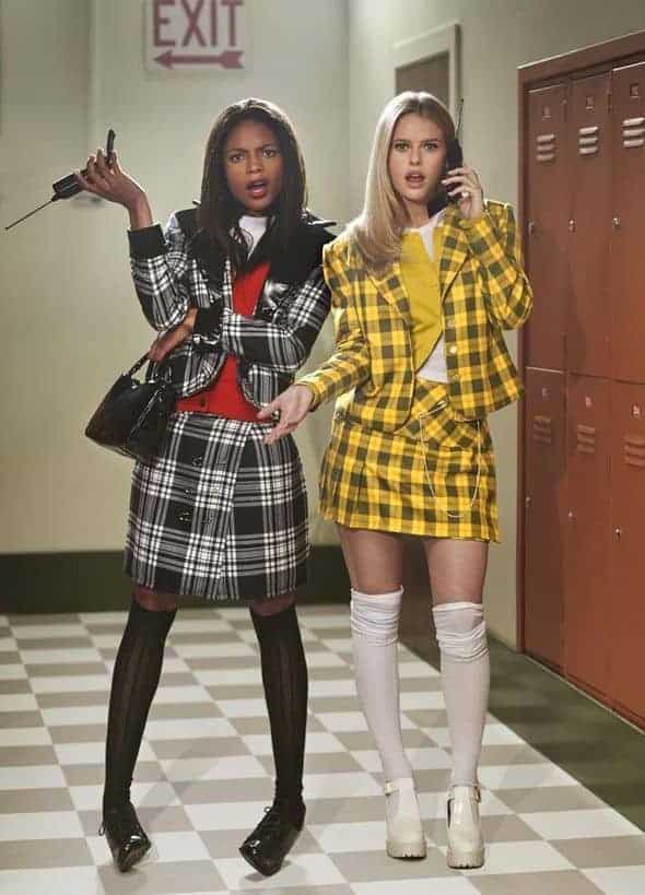 Trendy high school girls in plaid outfits standing by lockers in a colorful hallway.