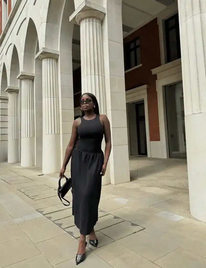 young woman wearing sleeveless black top and matching maxi skirt. old money outfit