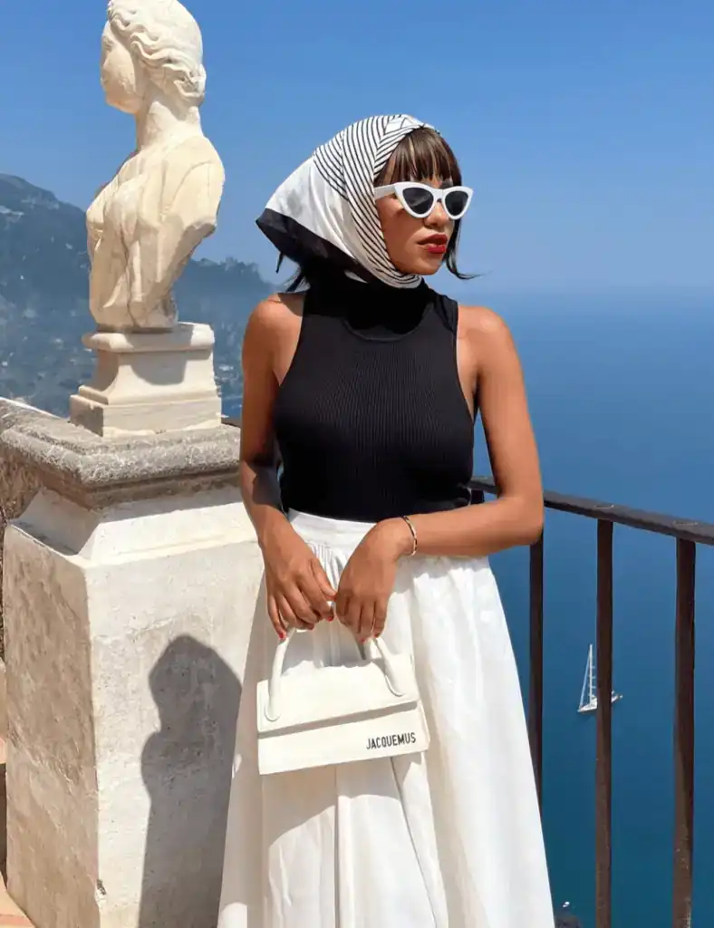young woman with wearing a old money style head scarf with sleeveless black top and maxi white skirt