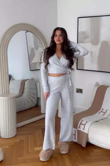 Woman in stylish grey loungewear set standing in modern living room, casual summer outfit.
