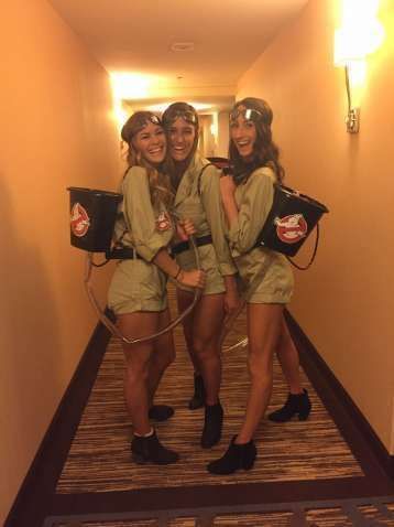 College girls in Ghostbusters costumes pose with homemade proton packs at a Halloween hotel party.