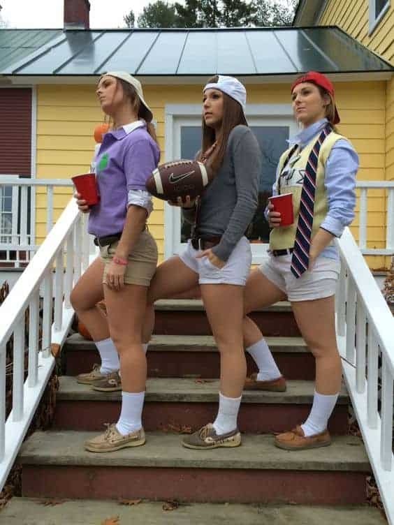 Trendy college Halloween costumes for best friends posing on stairs at autumn party.