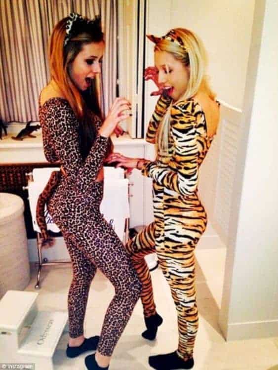 College girls in animal onesies having fun at costume party in modern bathroom.