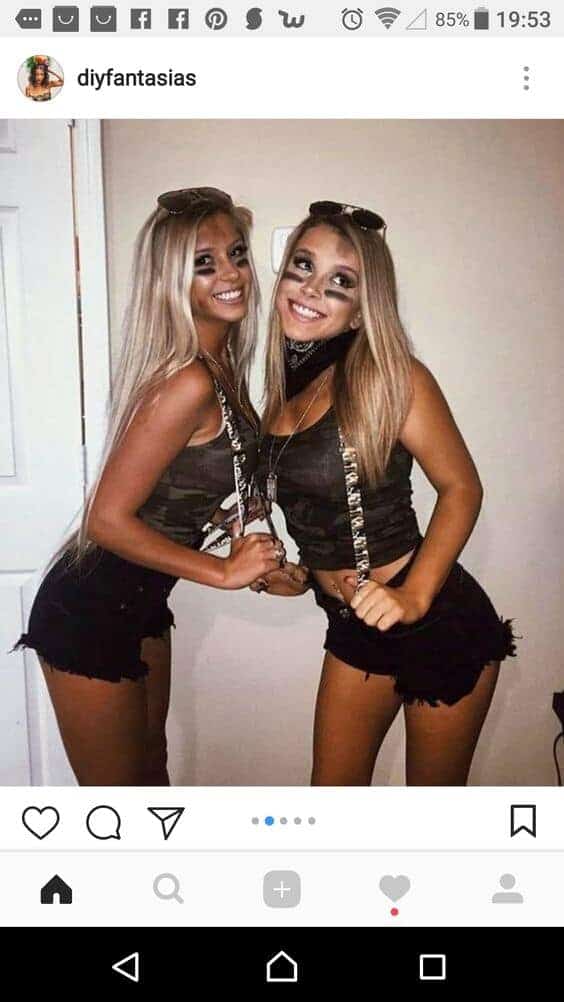 Two college girls in matching camo Halloween costumes posing and smiling for a party photo.