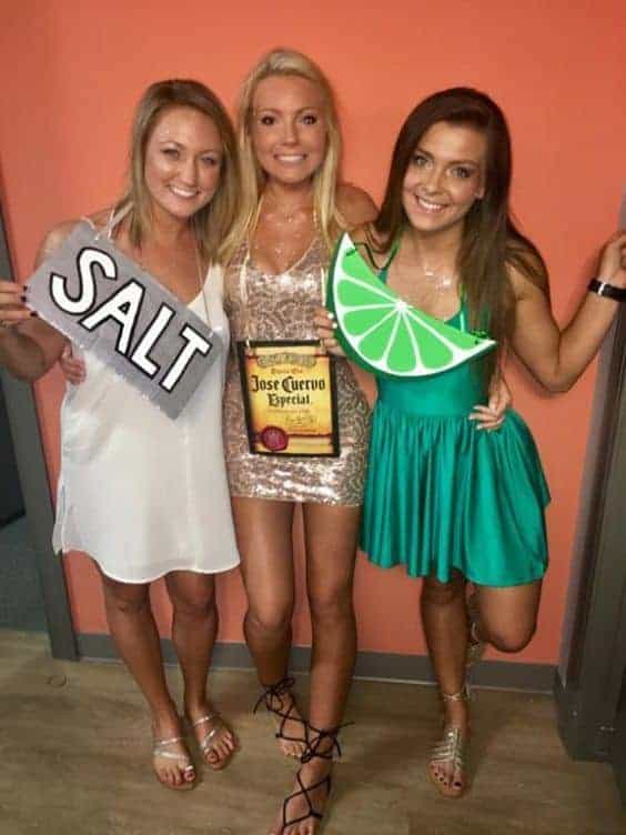Three women at a tequila-themed party with salt, lime, and Jose Cuervo props.