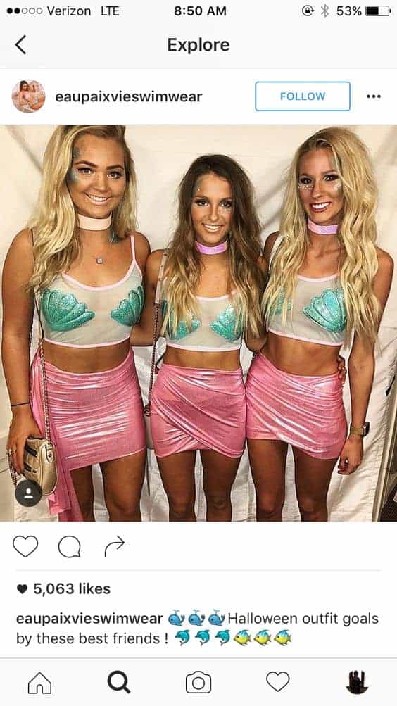 Three best friends in matching mermaid-inspired Halloween costumes, glitter seashell tops and pink skirts.