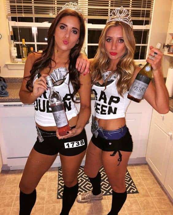 Best friends in matching Trap Queen Halloween costumes posing with drinks at a party.