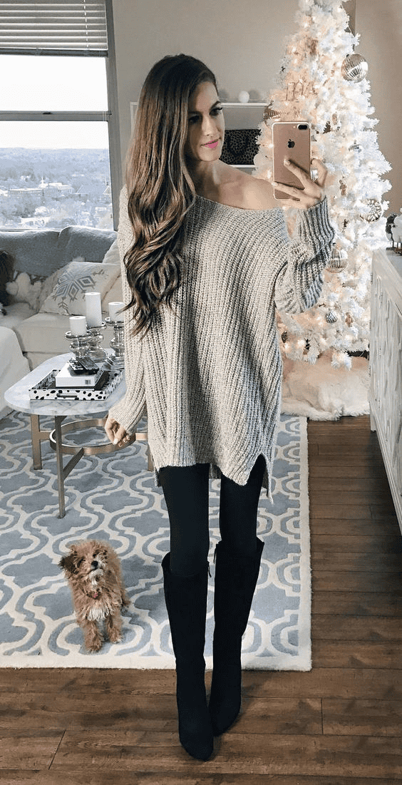 Cozy winter fashion selfie with woman in sweater, Christmas decor, and dog in stylish living room.