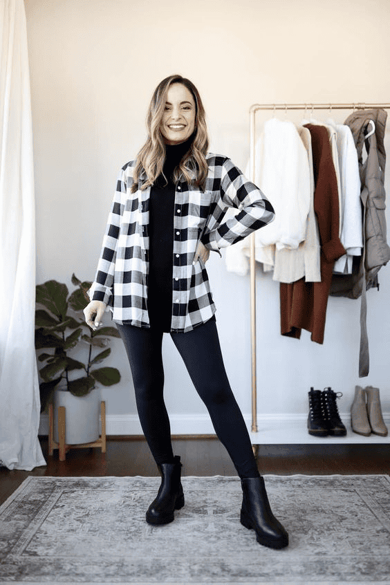 Woman in trendy checkered shirt and black leggings poses in modern, stylish, minimalist fashion room.