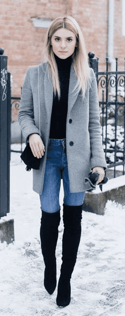 Stylish woman in grey coat and boots walking in snowy urban city street winter fashion.