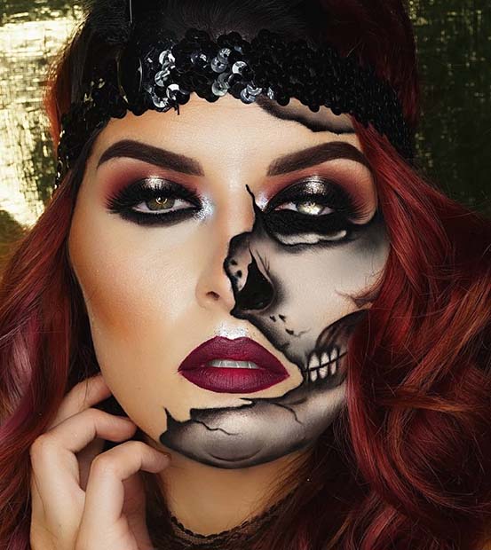 Half skull face Halloween makeup with red hair, glam eyeshadow, black headband, and gold background.