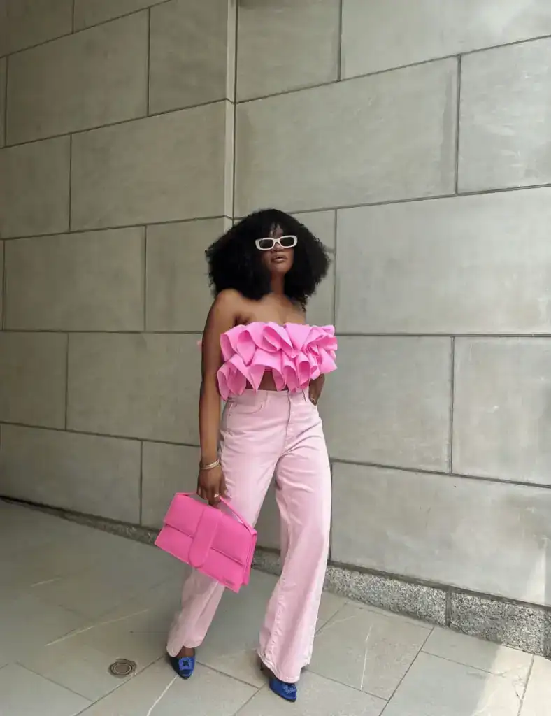 woman wearing pink ruffled top, pink denim jeans and a big pink bag