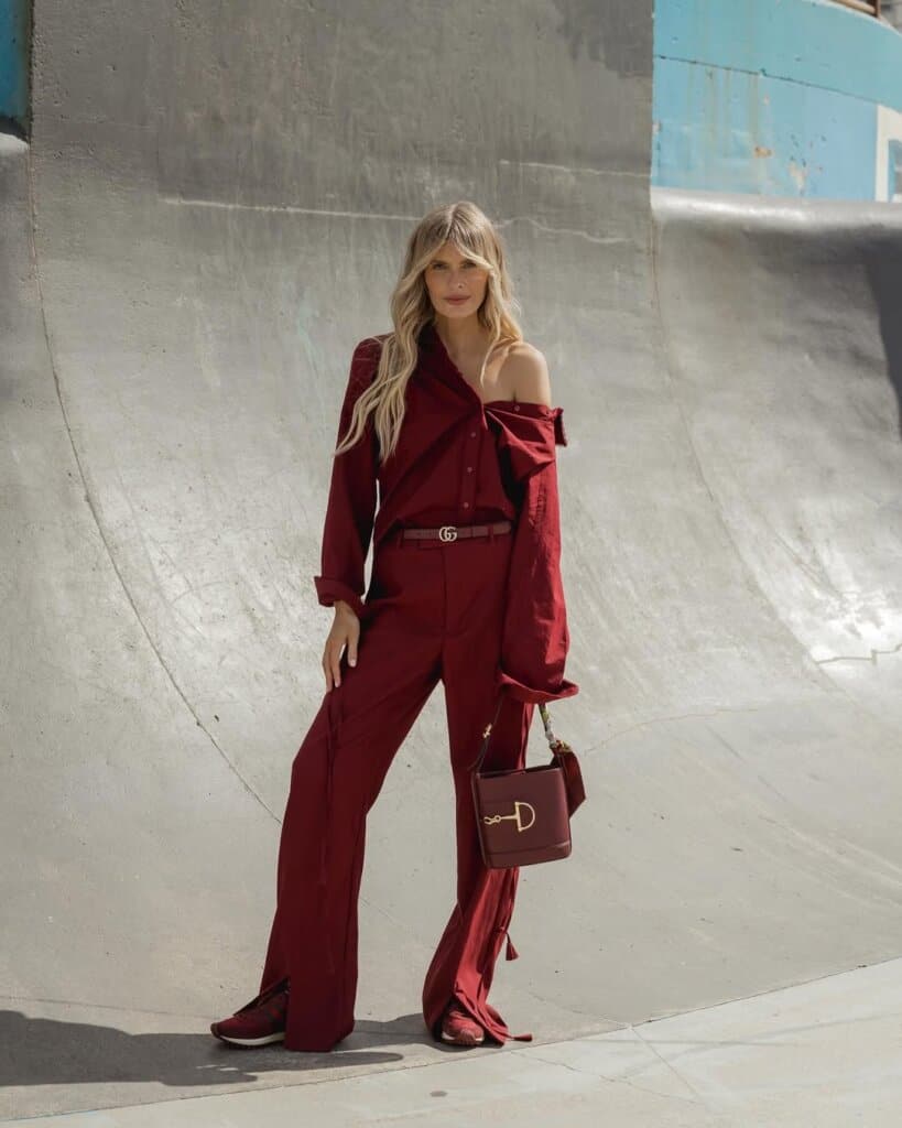Woman in burgundy street style outfit with Gucci belt posing at urban skatepark.