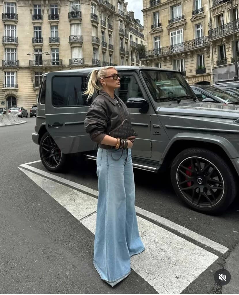 Stylish woman in oversized bomber jacket and wide-leg jeans on a Paris street, urban fashion trends.