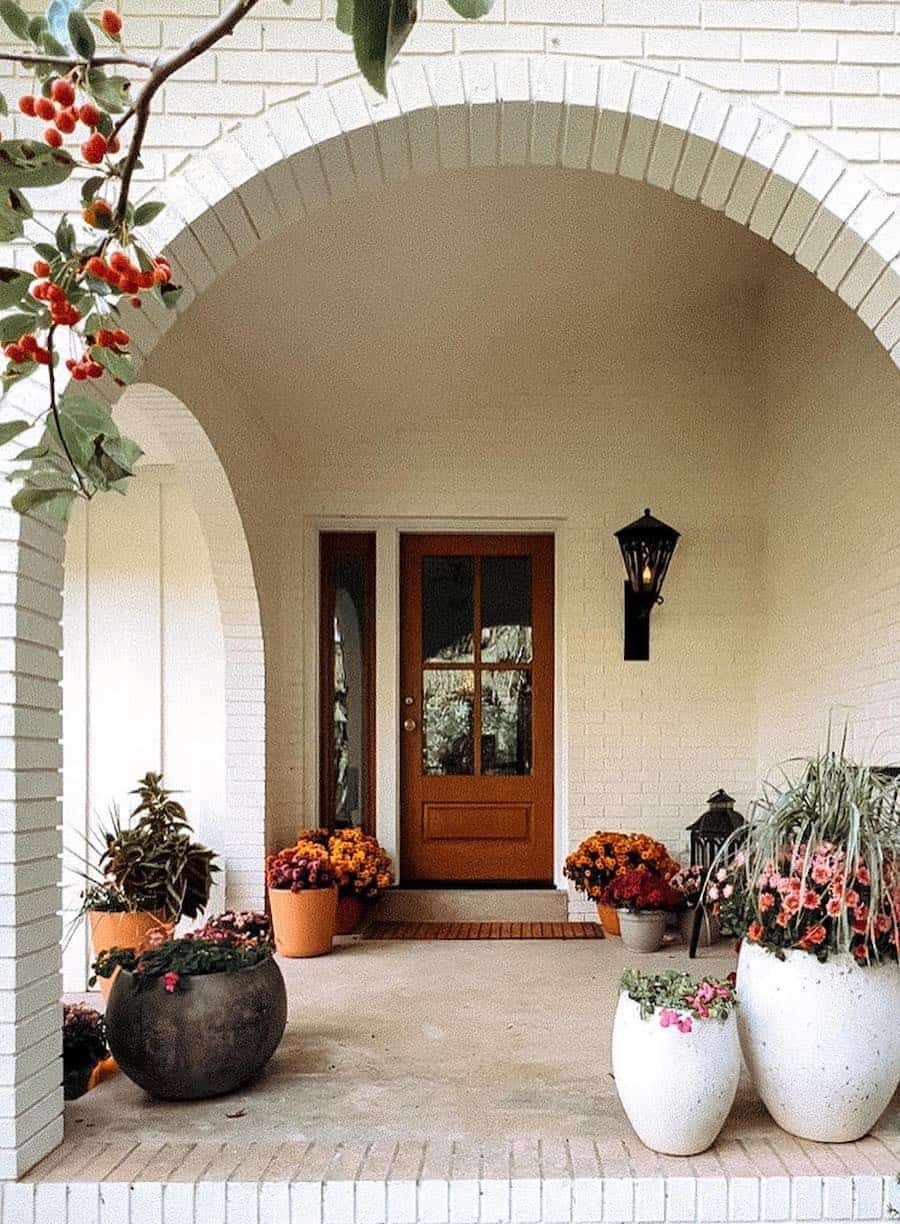 a front porch with fall floral arrangements