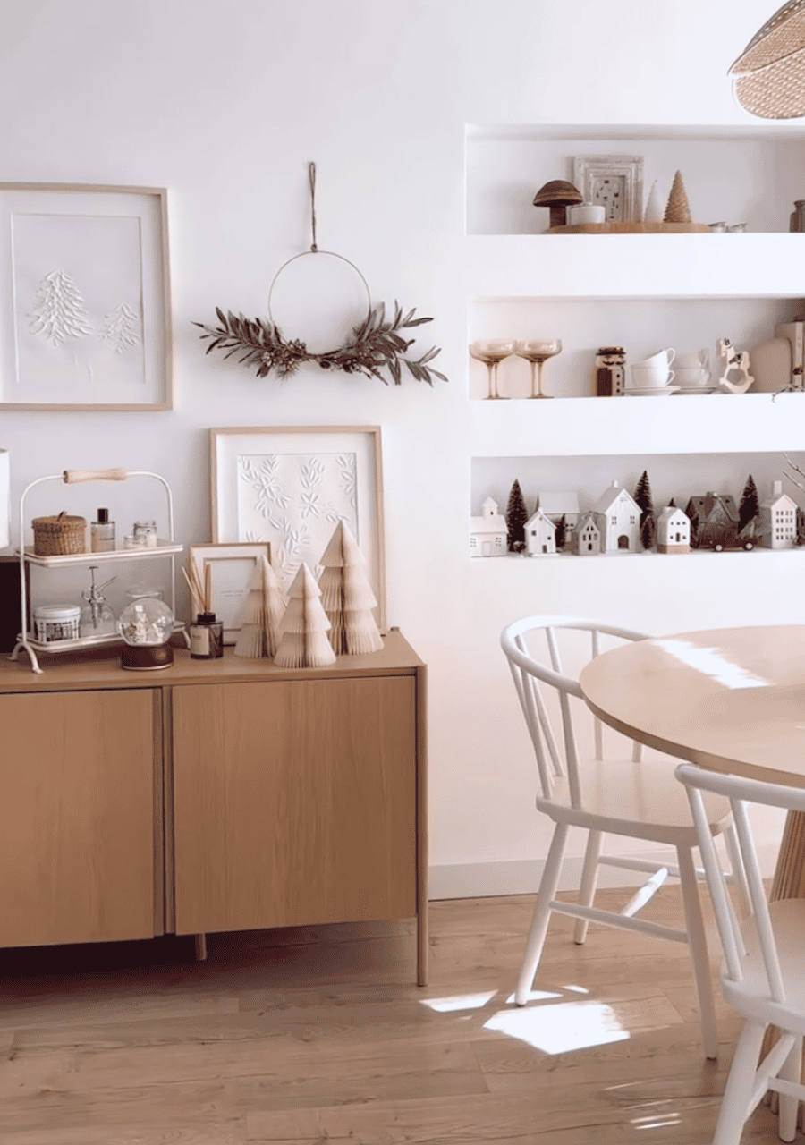 a dining room featuring indoor christmas decor including wooden trees, a minimalist wreath, and ceramic village decor