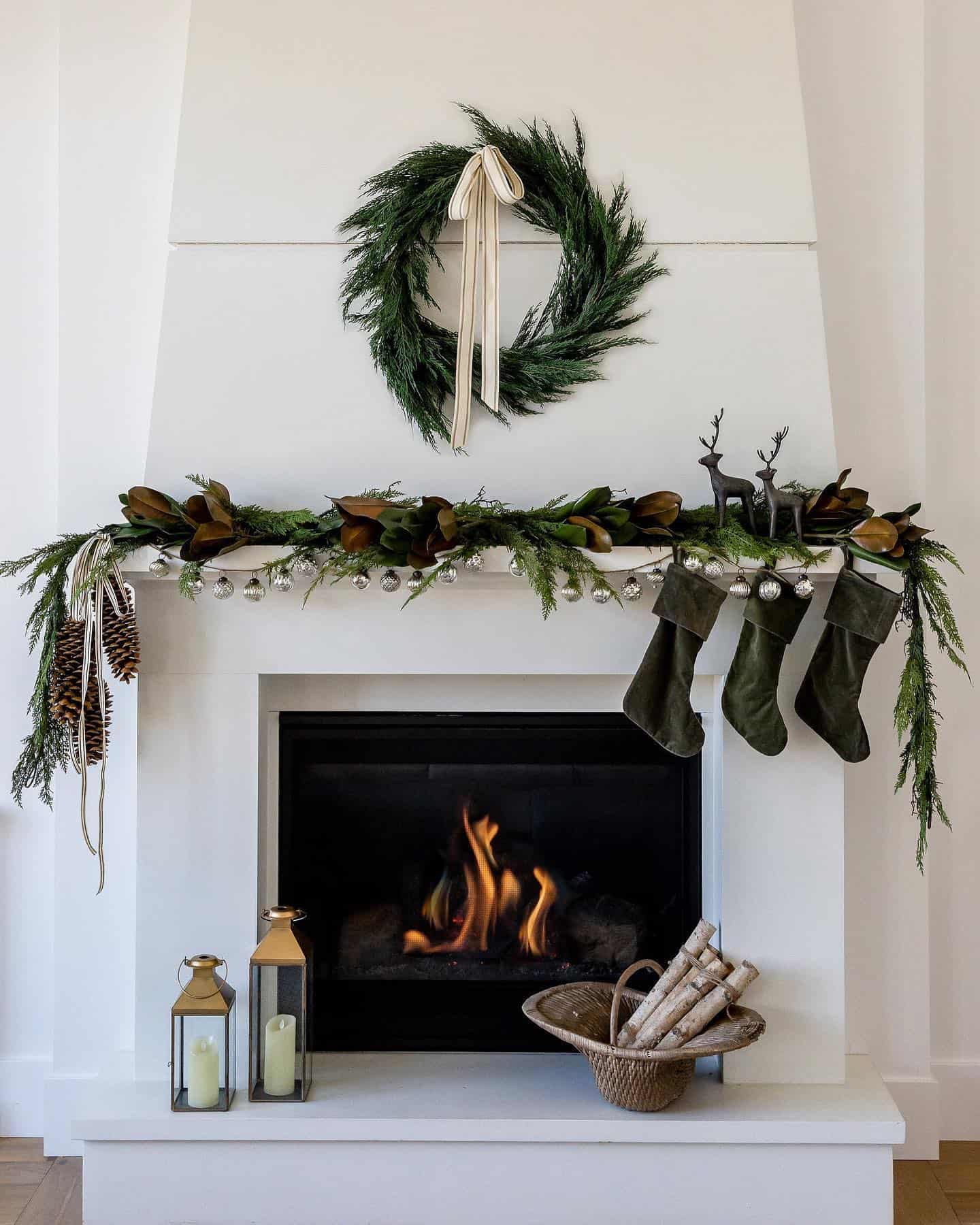 a white mantle with pine garland, pinecones, silver ornaments, velvet green stockings, and a pine wreath